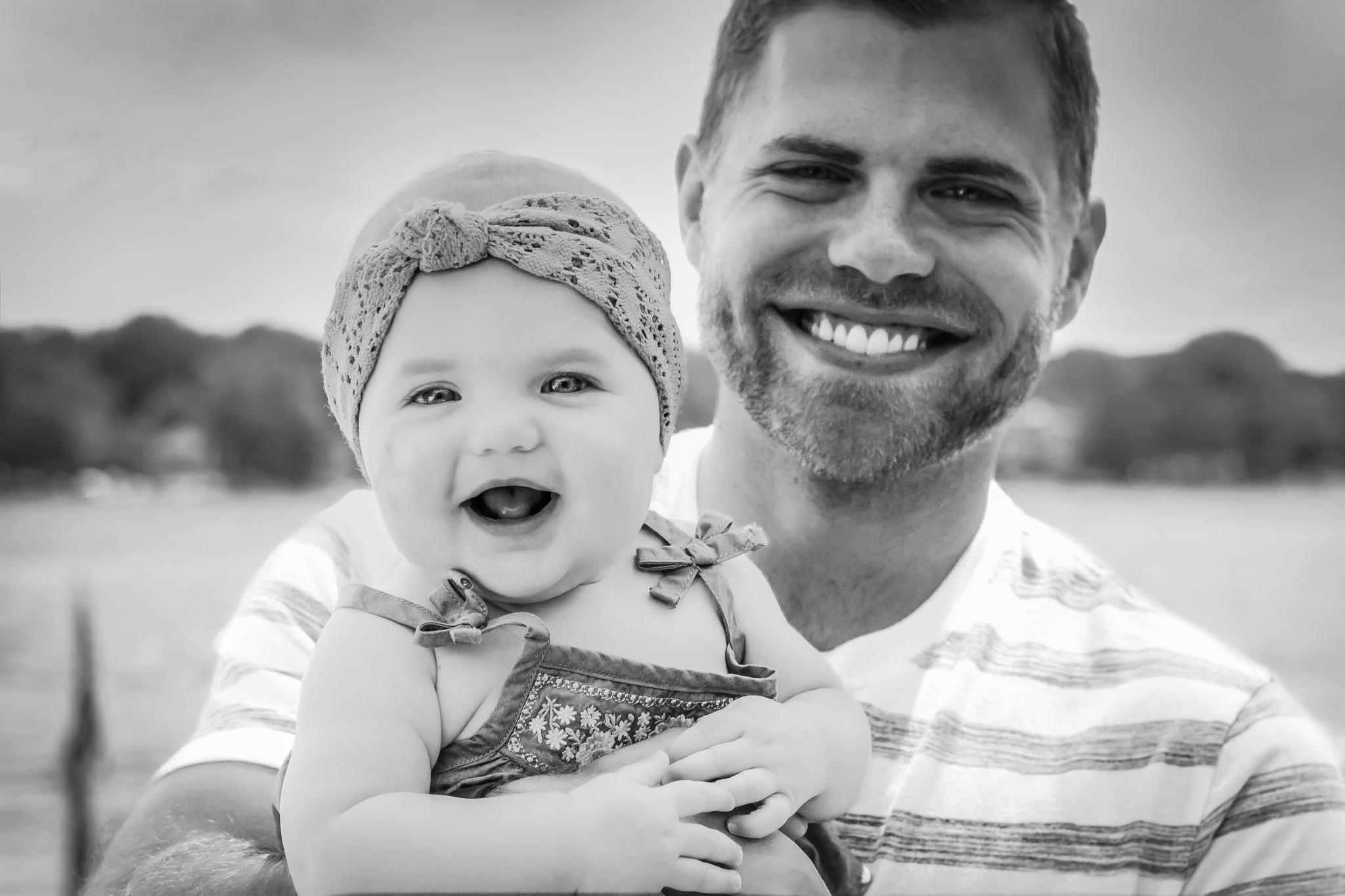 Young man and one-year-old daughter smiling at camera